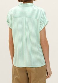 Short-sleeve green striped blouse with a collar, featuring a back yoke and loose fit. Fabric appears lightweight and smooth.