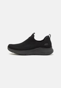 Black slip-on sneaker with a breathable mesh upper, padded collar, and lightweight EVA sole. Features a textured surface and minimal branding.