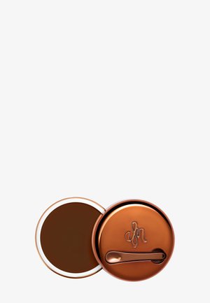 Kompakte Kupfermetalldose in runder Form, mit glänzender Oberfläche und eingraviertem Logo. Der Deckel öffnet sich und zeigt eine dunkelbraune Creme im Inneren.