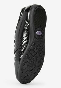 Schwarze Lackleder-Schuhe mit runder Zehenform, ausgestattet mit einer strukturierten Gummisohle im Herzmuster und einem Klettverschluss zum Sichern.