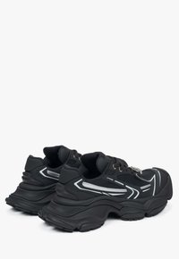 Czarne buty sportowe wykonane z materiałów siatkowych i syntetycznych, z odblaskowymi akcentami oraz masywną podeszwą. Związane wzmocnionymi oczkami.