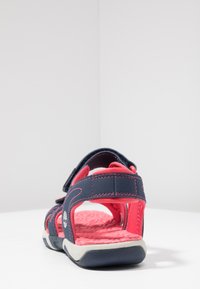 Navy blue sandal with pink accents, featuring a textured insole, adjustable straps, and a durable rubber sole. Rear view shown.