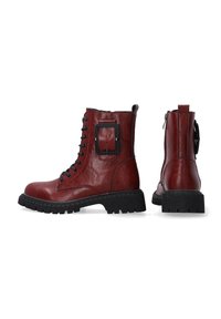 Red leather ankle boots with a textured black rubber sole, lace-up front, and a decorative buckle detail on the side.