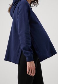 Navy blue hoodie with a relaxed fit, featuring long sleeves and side slits for added comfort. Soft fabric texture and simple design.