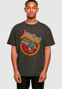 Černé, oversized bavlněné tričko s barevným grafickým potiskem zobrazujícím dráp a textem "Judas Priest" tučnými písmeny.