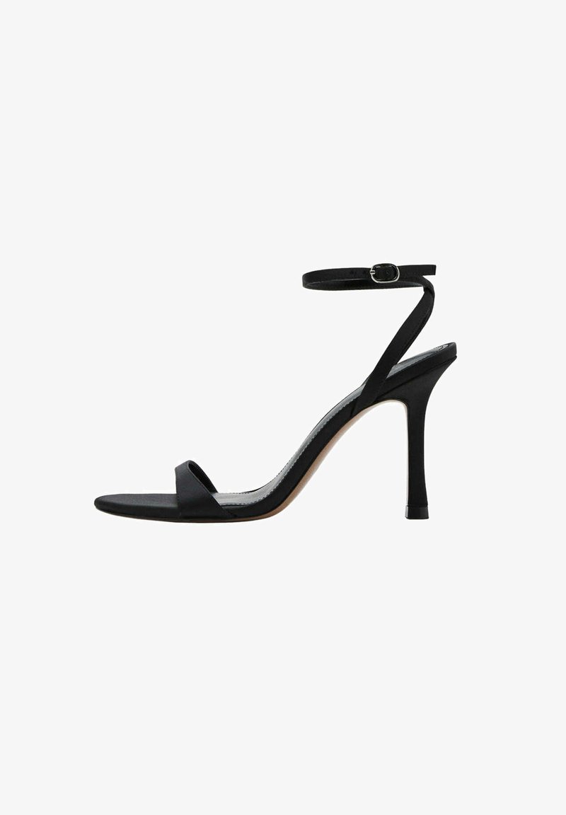 Sandale noire à talon haut avec fine bride cheville et boucle, bout ouvert et talon aiguille fin sur fond blanc.