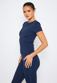 Mörkblå åtsittande T-shirt i slätt tyg med korta ärmar, rund halsringning och subtila sömmar, parat med matchande leggings.