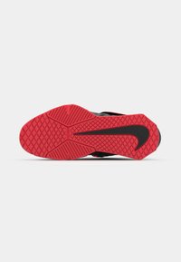 Nike shoe outsole features a textured red rubber surface with black accents and a prominent black swoosh logo.