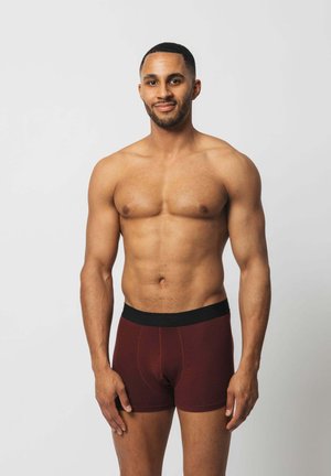 Burgunderfarbene Boxer-Briefs mit einem schwarzen elastischen Bund, ausgestattet mit einer glatten Textur und kontrastierenden Nähten.