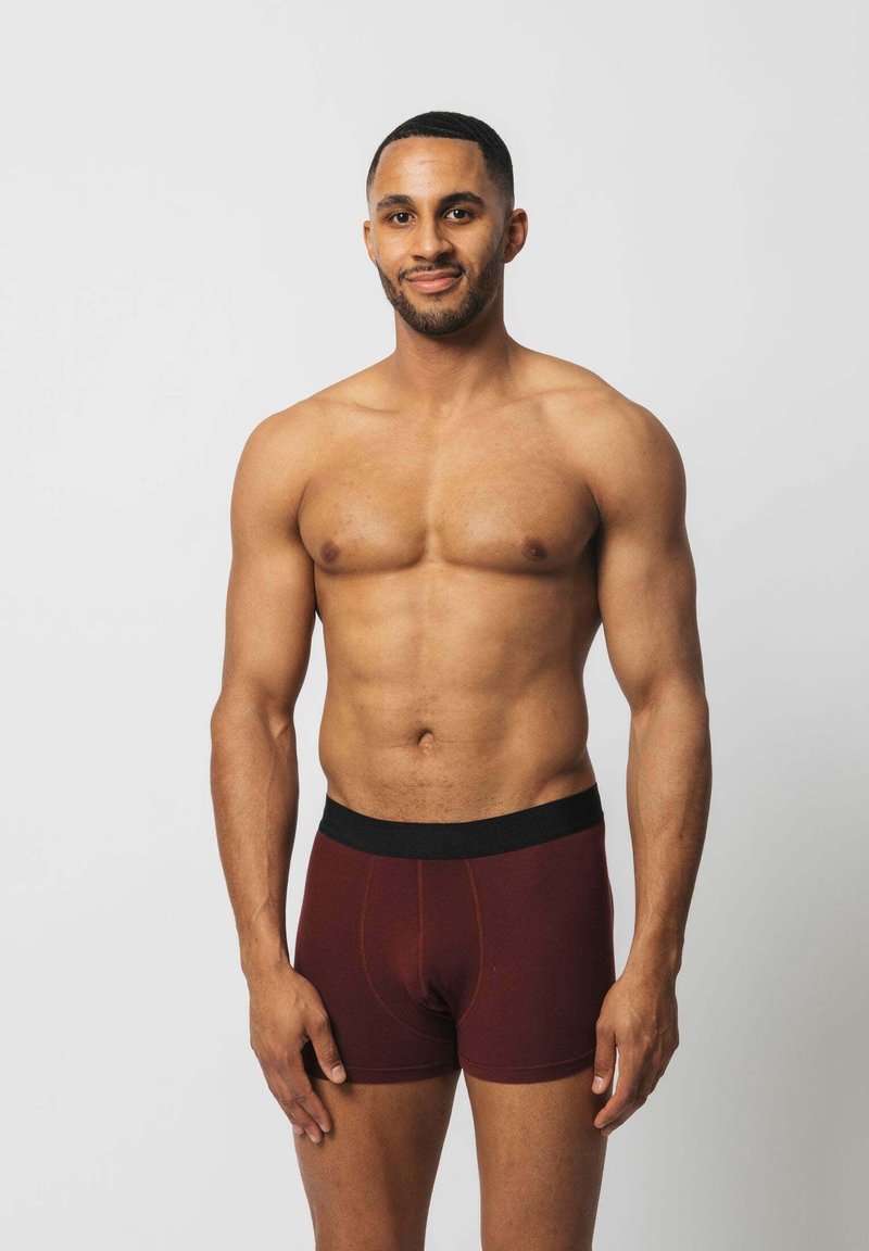 Burgunderfarbene Boxer-Briefs mit einem schwarzen elastischen Bund, ausgestattet mit einer glatten Textur und kontrastierenden Nähten.