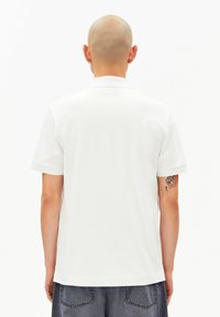 Wit poloshirt met een klassieke kraag en korte mouwen, gemaakt van ademende stof. Heeft een gladde textuur en een minimalistisch ontwerp.