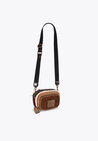 Torebka crossbody w wzór zwierzęcy z akcentami z sztucznego futra, brązowymi zamykanymi komorami i regulowanym czarnym paskiem. Zawiera dekoracyjne elementy metalowe.