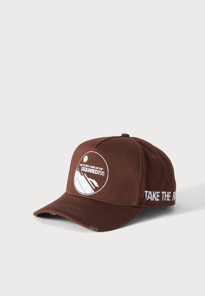 Gorra de béisbol marrón con gráfico blanco y texto "DSQUARED295" en el frente y "TAKE THE RISK" en el lateral, visera ligeramente desgastada.