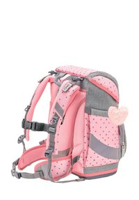 Rosa Rucksack mit Pünktchenmuster und grauen Akzenten, gepolsterten Trägern, Netzpaneelen, einer Fronttasche und einem flauschigen Herzschlüsselanhänger.