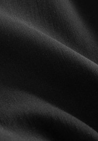 Tissu noir lisse avec des plis subtils et une texture de tissage fin visible sous un éclairage doux.