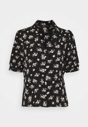 Blusa nera a maniche corte con motivo floreale in rosa chiaro, colletto a punta e chiusura frontale con bottoni. Texture del tessuto morbida.