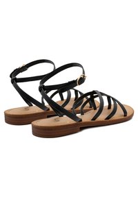 Sandali neri con cinturini, suola piatta e una soletta marrone texturizzata. Presentano cinturini eleganti e una fibbia dorata per una vestibilità regolabile.