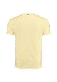 Jasnożółta, krótko rękawowa koszulka pokazana z tyłu, z małą metalową metką logo blisko kołnierza.