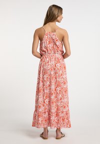 Rochie maxi cu un model paisley roșu și alb. Are bretele subțiri, talie strânsă și tiv evazat. Material ușor, design fără spate.