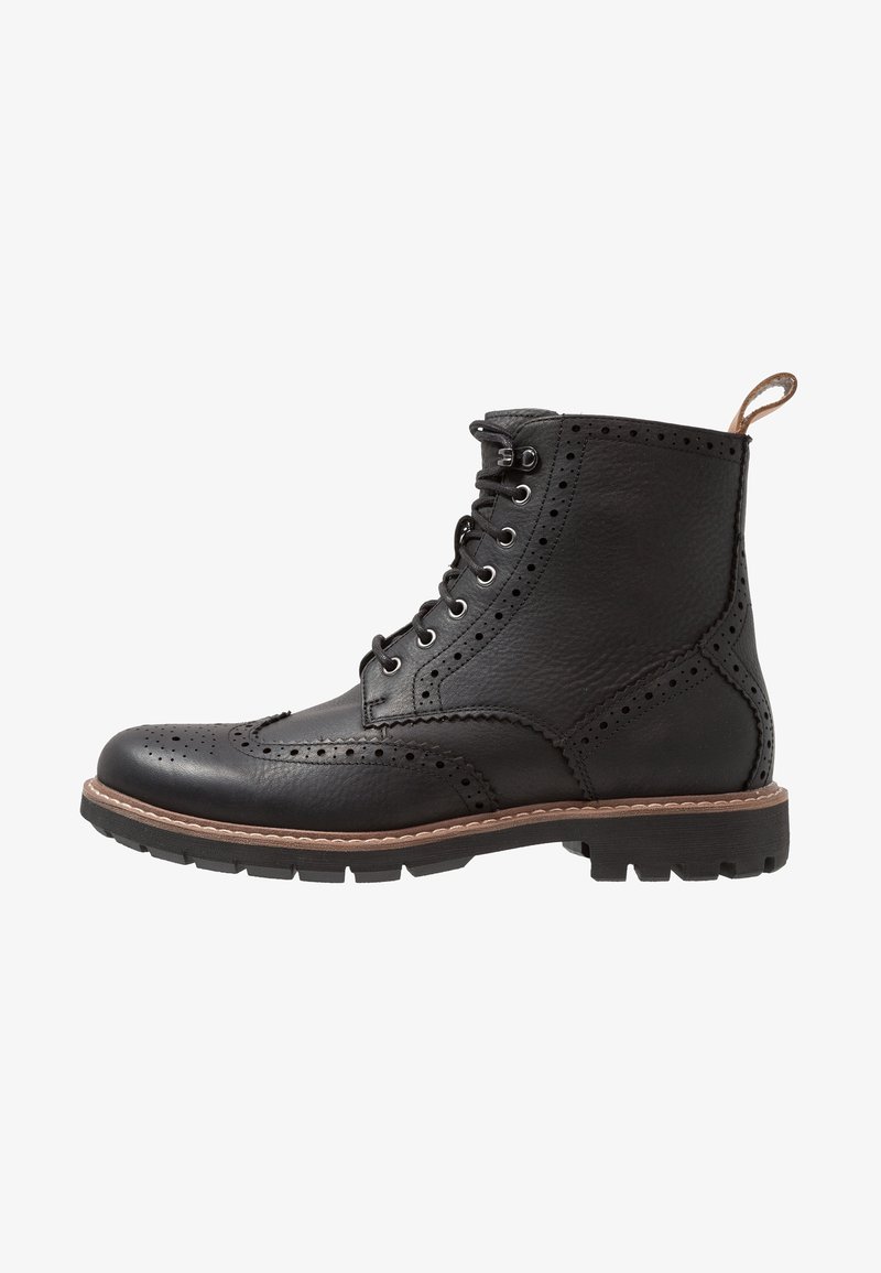 Bottine brogue en cuir noir avec fermeture à lacets à l'avant, détails perforés, languette beige et semelle en caoutchouc robuste.
