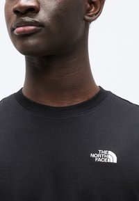 Μαύρο βαμβακερό t-shirt με στρογγυλή λαιμόκοψη, που διαθέτει μικρό λευκό κεντημένο λογότυπο του "The North Face" στην αριστερή πλευρά του στήθους.