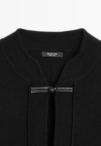 Schwarze Sweater mit Rundhalsausschnitt, ausgestattet mit einem Schlüssellochverschluss und einem dekorativen Lederband mit Knopfakzent. Weiches Strickmaterial.