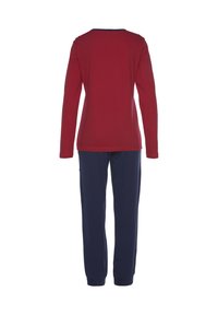 Red long-sleeve top with a crew neckline paired with navy blue pants. Soft cotton fabric, relaxed fit, and elastic cuffs at the pant legs.