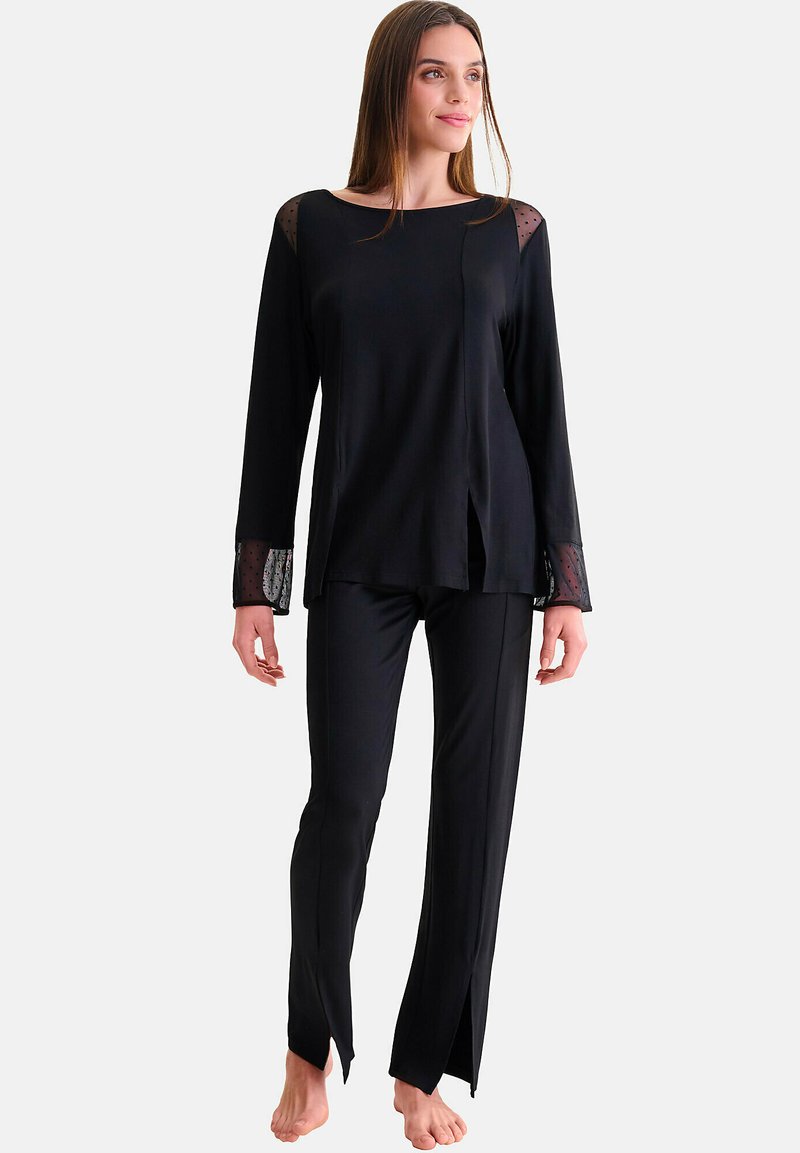 Zwart loungewearset bestaande uit een langemouwen top met gaas schouderaccenten en zijsplitten, gecombineerd met rechte broekspijpen. Soepele textuur.