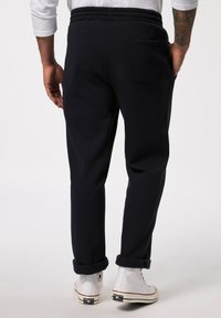 Marineblaue Sweatpants mit elastischem Bund, am Knöchel gerafft, ausgestattet mit einer Gesäßtasche und einer glatten Baumwolltextur.