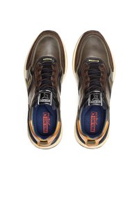 Zapatillas de cuero marrón con acentos negros, punta redonda, diseño de cordones, cuello acolchado y suela texturizada con logo visible y detalles de color.