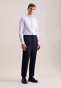 Lichtblauw overhemd met kraag, lange mouwen, marineblauwe broek met hoge taille en zwarte leren schoenen. Gladde stof, getailleerde pasvorm en klassiek ontwerp.