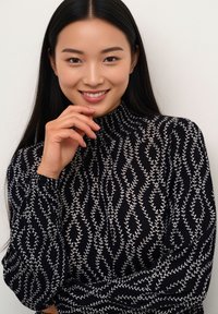 Zwart top met lange mouwen met een hoge halslijn en een wit bloemenpatroon. De stof heeft een getextureerde afwerking met geplooide details bij de mouwen.