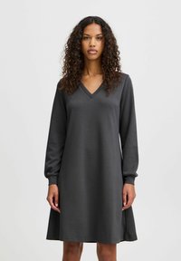 Dunkelgraues langärmliges Kleid mit V-Ausschnitt, aus einem glatten Stoff gefertigt, mit entspannter Passform und dezenten Seitenschlitzen für mehr Bewegungsfreiheit.