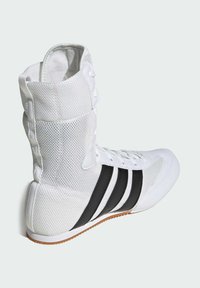 Weißer Sportschuh mit Mesh-Material, drei schwarzen Streifen und einer Gummisohle. Verfügt über eine Schnürung vorne und gepolsterten Knöchelbereich.