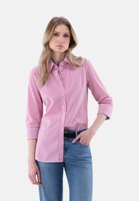 Striped button-up shirt in pink and white, featuring a collared neck and three-quarter sleeves, paired with blue jeans and a black belt.