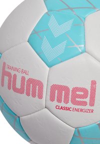 Palla da allenamento da calcio bianca e turchese con pannelli esagonali, dotata di superficie testurizzata, un marchio rosso audace e accenti a motivo chevron.