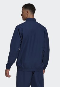 Mariene blauwe sportjack met een hoge kraag, elastische manchetten en tailleband, met een gladde textuur en eenvoudig ontwerp.