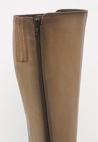 Bota de cuero marrón hasta la rodilla con cremallera lateral y detalle de costura vertical. Textura suave con borde superior redondeado.