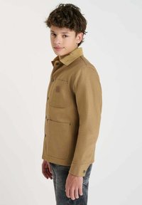 Tan jacket met een corduroy kraag, voorkuur en knoopsluitingen. Ontworpen met een rechte pasvorm, met een gladde textuur.