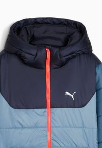 Kapuzenschalenjacke mit einem navyblauen Oberteil und einem hellblauen Unterteil, ausgestattet mit einem leuchtend orangefarbenen Reißverschluss und einem weißen Logo-Akzent auf der Brust.