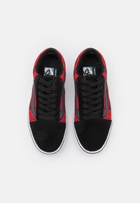 Baskets noires et rouges avec une tige en daim et textile, présentant un motif texturé, des lacets noirs et une semelle extérieure en caoutchouc blanche.