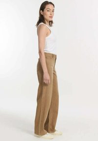 Brede bruine denim broek met hoge taille en voorzakken, gecombineerd met een witte tanktop en casual schoenen.