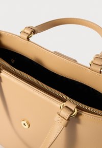 Borsa a tracolla in pelle color cuoio con due manici, una tasca frontale con chiusura magnetica e una zip superiore che mostra una fodera interna nera.