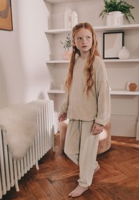 Completo da casa in velluto a coste beige composto da una maglia a maniche lunghe dalla vestibilità ampia e pantaloni abbinati. Tessuto morbido e motivo a coste.