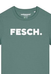 Grünes T-Shirt aus weichem Stoff mit fettem weißen Text "FESCH." in einer serifenlosen Schriftart. Rundhalsausschnitt und kurze Ärmel.