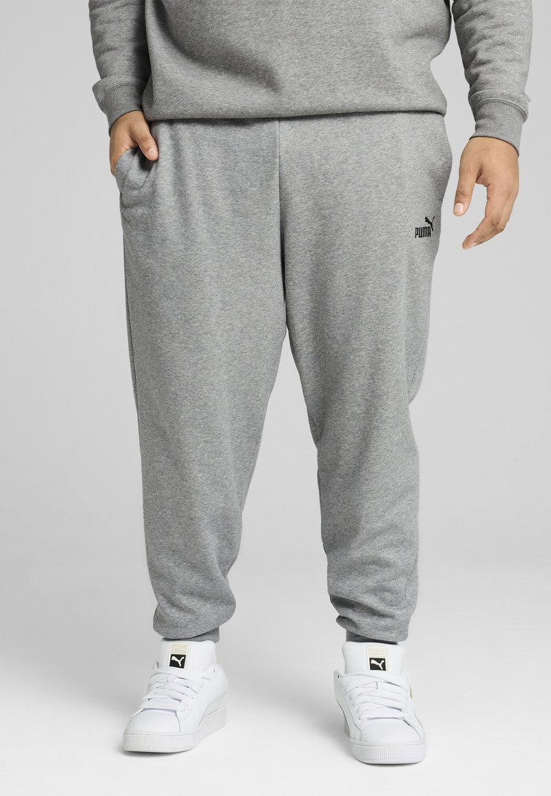 Grå bomulds sweatpants med elastisk talje, sidelommer og lille sort Puma-logo på venstre lår. Parret med hvide sneakers.