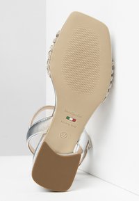 Sandale à talons argenté métallique avec un dessus lisse, des accents en perles délicates sur les brides et une semelle en caoutchouc beige étiquetée taille 37.
