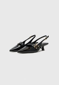 Črne patent usnjene slingback pete s koničastim nosom, ki imajo trak z zlatimi zaponkami in nizko kvadratno peto.