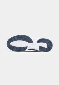 Shoe outsole featuring a white midsole, textured black rubber tread with a patterned grip, and a logo detail in the center.