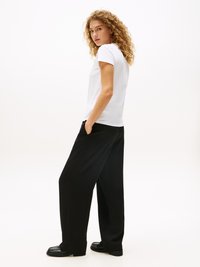 White short-sleeve t-shirt paired with black wide-leg trousers, featuring a smooth fabric texture and simplistic design. Black loafers complete the outfit.